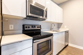 A modern kitchen with white cabinets and stainless steel appliances.